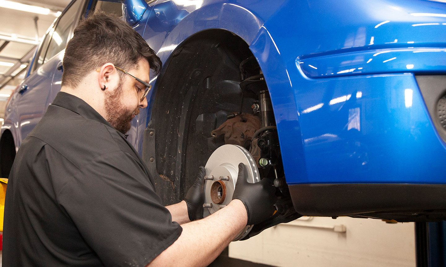 Steering and suspension repair McCabe’s technician working on a front wheel and brake rotor